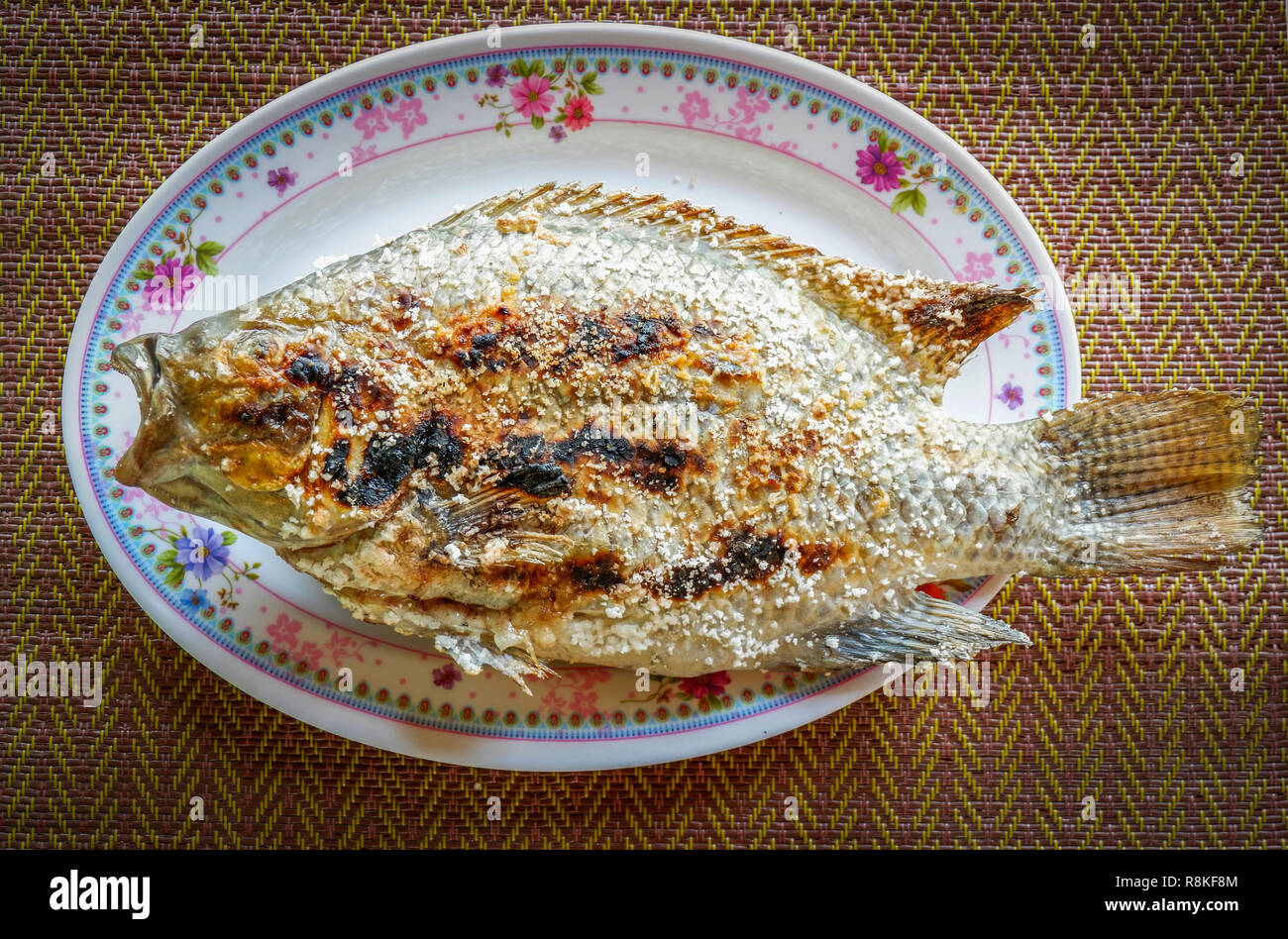 Grillades de poisson Tilapia tilapia grillé à l'/ Sel dans l'alimentation de style asiatique sur platine - Gravure de poisson Tilapia thaïlandais aux herbes brûlées Banque D'Images