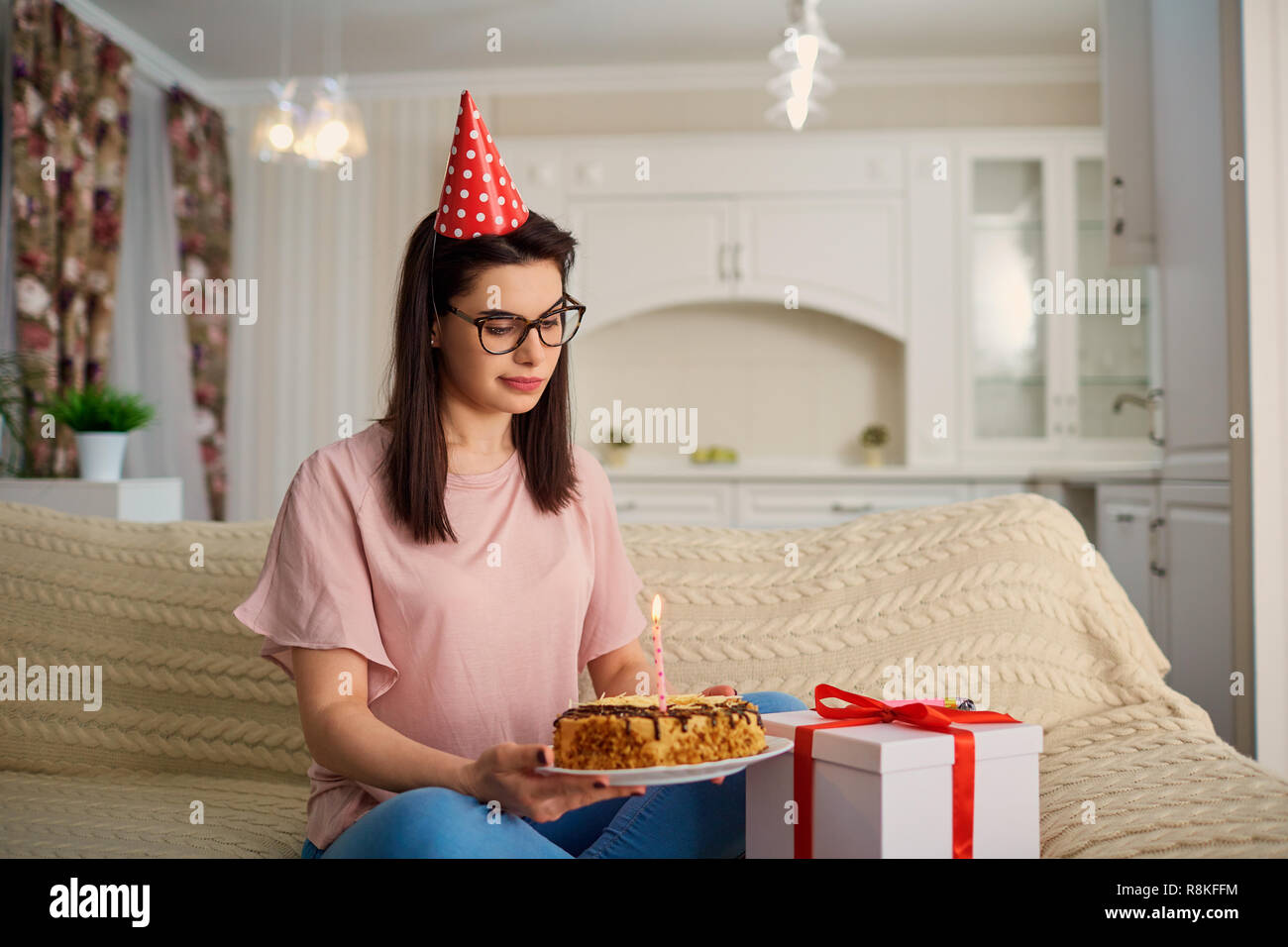 Une malheureuse fille portant un chapeau pour son anniversaire avec un gâteau avec c Banque D'Images