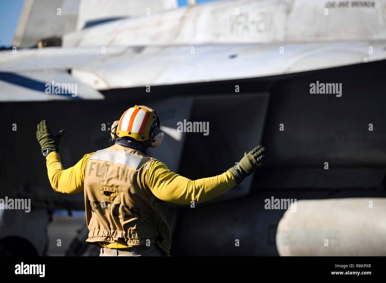 Un directeur de vol dans une chemise jaune, le signal d'un F/A-18 Super Hornet à bord du porte-avions de classe Nimitz USS Harry S. Truman le 7 décembre 2018 dans l'océan Atlantique. Chemises jaunes sont portés par les gestionnaires d'aéronefs Aéronefs, administrateurs, officiers et catapulte Agents Arrêt considéré comme le plus difficile et important travail sur le poste de pilotage. Banque D'Images
