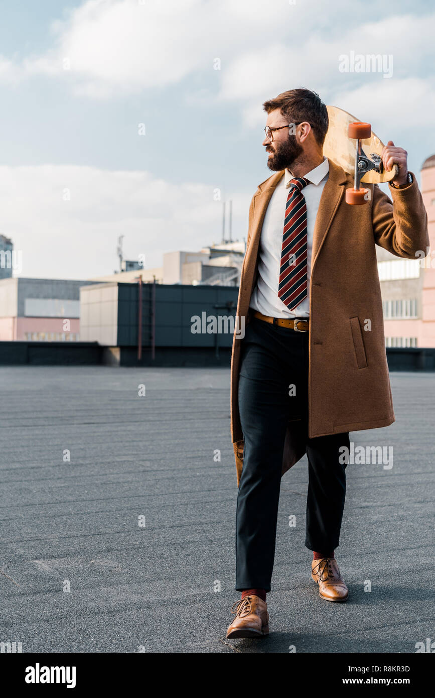Homme d'affaires réussi en soirée et enduire la marche avec penny board Banque D'Images
