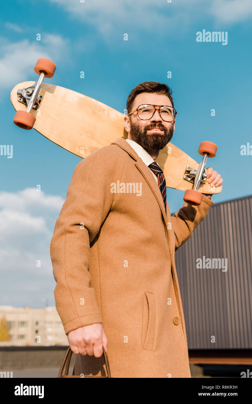 Smiling businessman in glasses holding penny board Banque D'Images