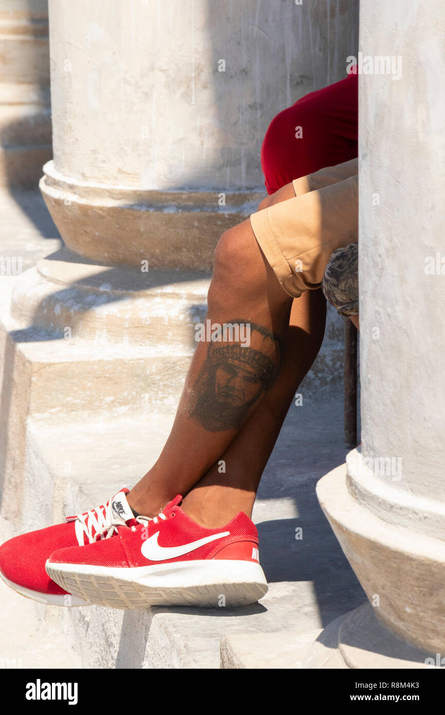 Détail de jeunes tatoués les jambes, assis au soleil à La Havane, Cuba Banque D'Images