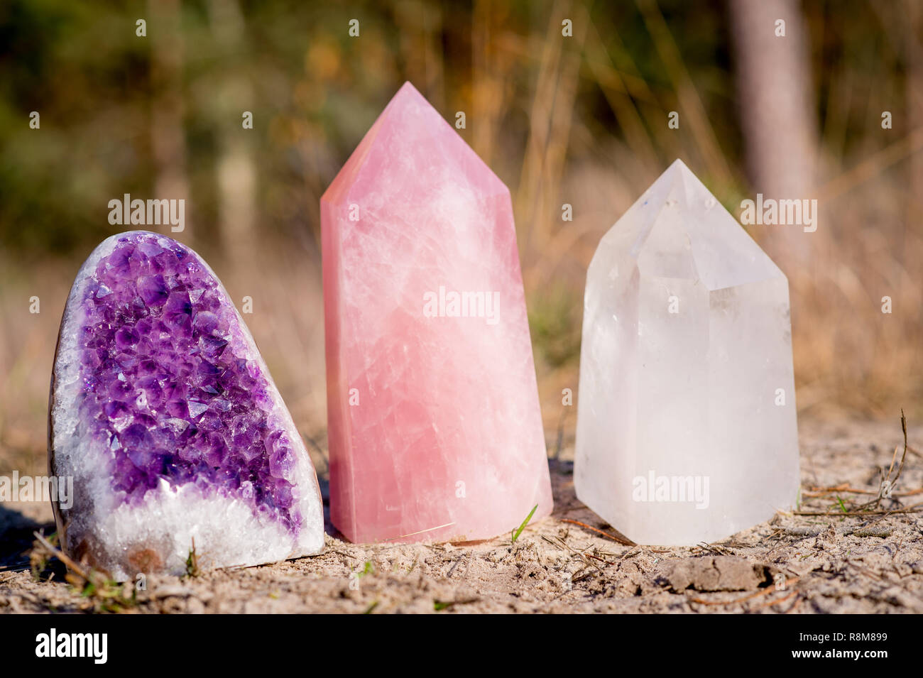 Triangle d'or pierres précieuses : Améthyste, quartz rose et quartz blanc, debout ensemble dans l'herbe Banque D'Images