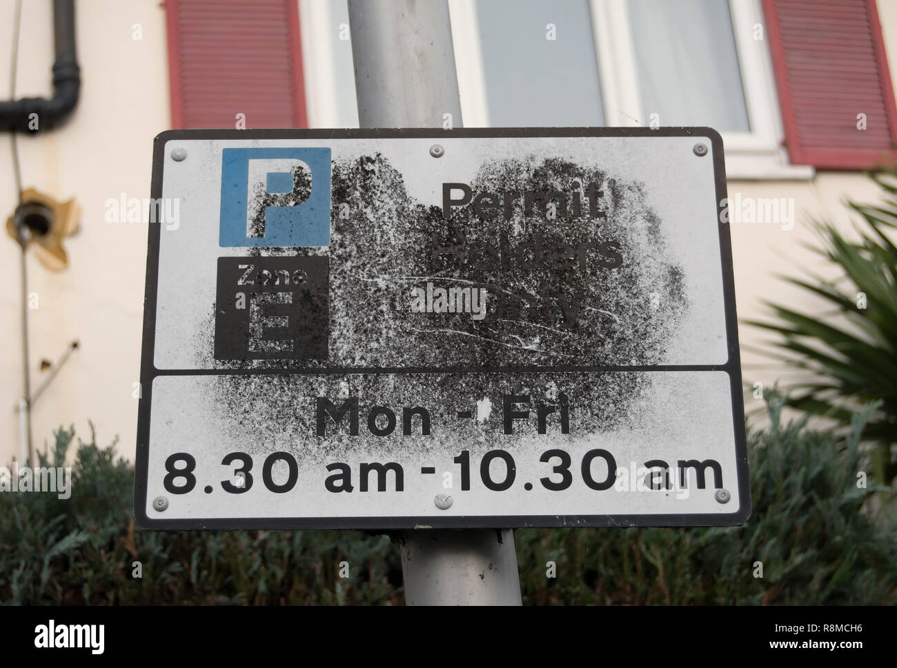 Partiellement masquée british road sign detalls donnant des restrictions de stationnement de rue, à Twickenham, Middlesex, Angleterre Banque D'Images