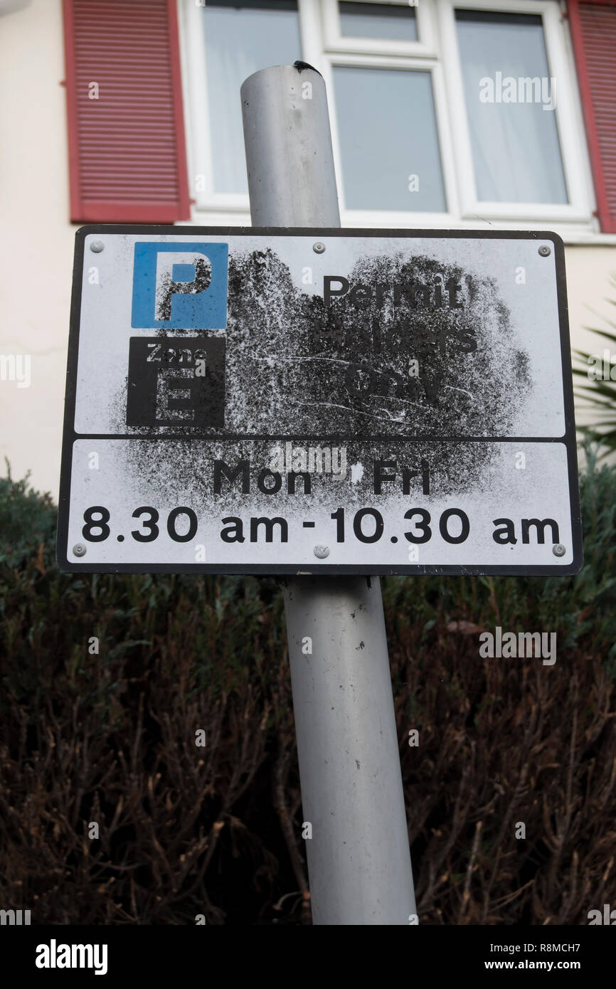 Partiellement masquée british road sign detalls donnant des restrictions de stationnement de rue, à Twickenham, Middlesex, Angleterre Banque D'Images