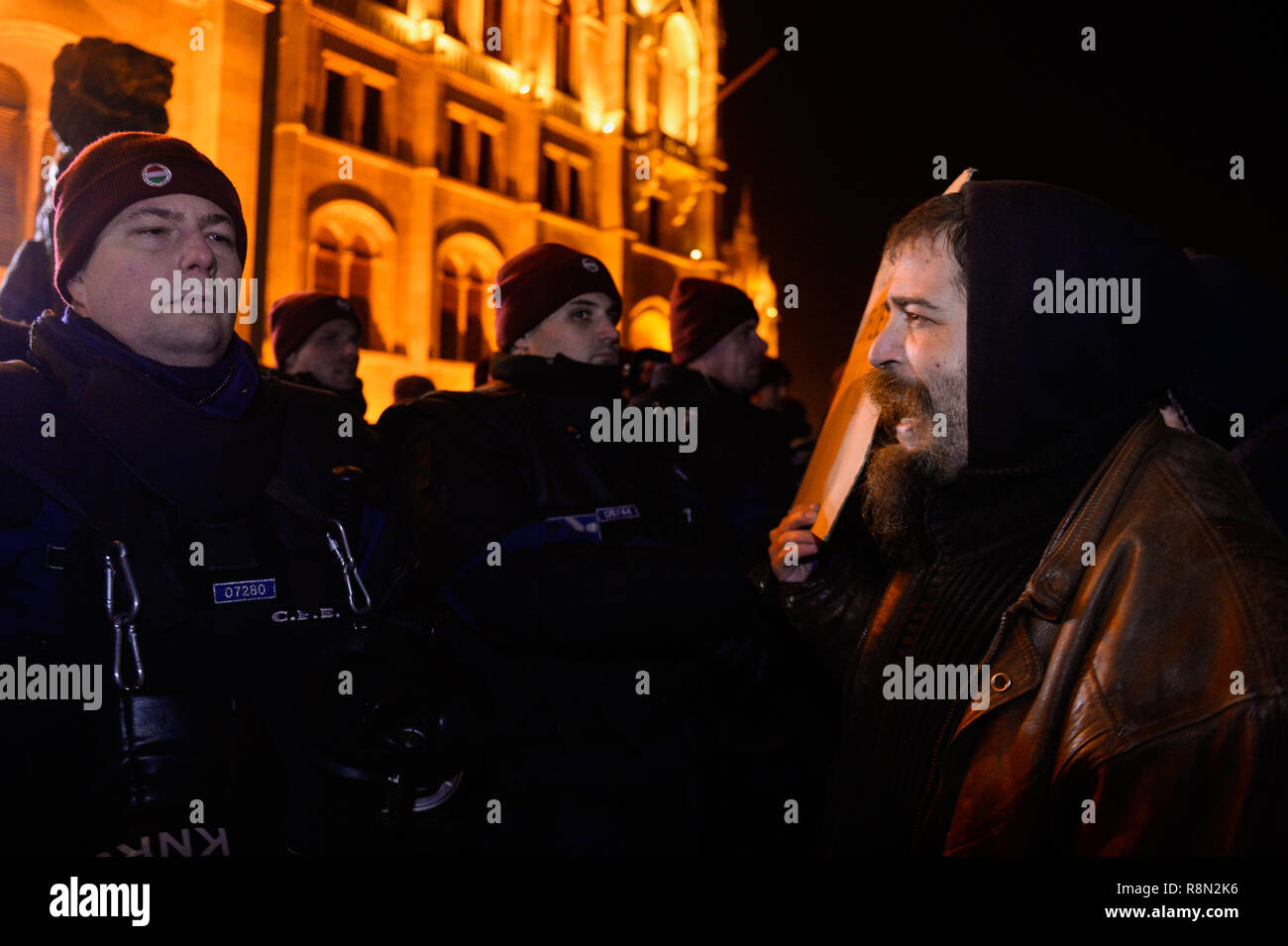 Budapest, Hongrie. Dec 16, 2018. Un manifestant vu holding a placard comme il parle à un agent de police au cours de la protestation contre la nouvelle législation du travail approuvé par l'aile droite du gouvernement conservateur dirigé par Viktor Orban. Le gouvernement hongrois a adopté un ensemble de lois controversées sur l'entraide judiciaire et du travail sujets, la nouvelle loi sur le travail, connu sous le nom de 'slave' la loi permet aux employeurs de demander à leurs travailleurs de prendre sur jusqu'à 400 heures supplémentaires par an. Credit : SOPA/Alamy Images Limited Live News Banque D'Images