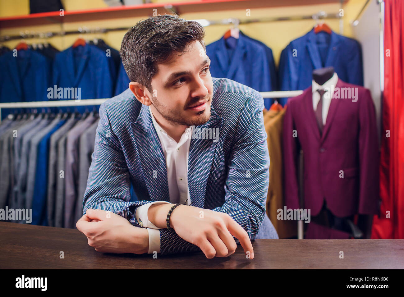 Tailleur, couture. Men's costume, tailleur dans son atelier. Les costumes  de l'homme élégant en ligne. Costumes de luxe classique mens sur rack dans  un élégant boutique hommes choisissant fatigué des bâillements Photo