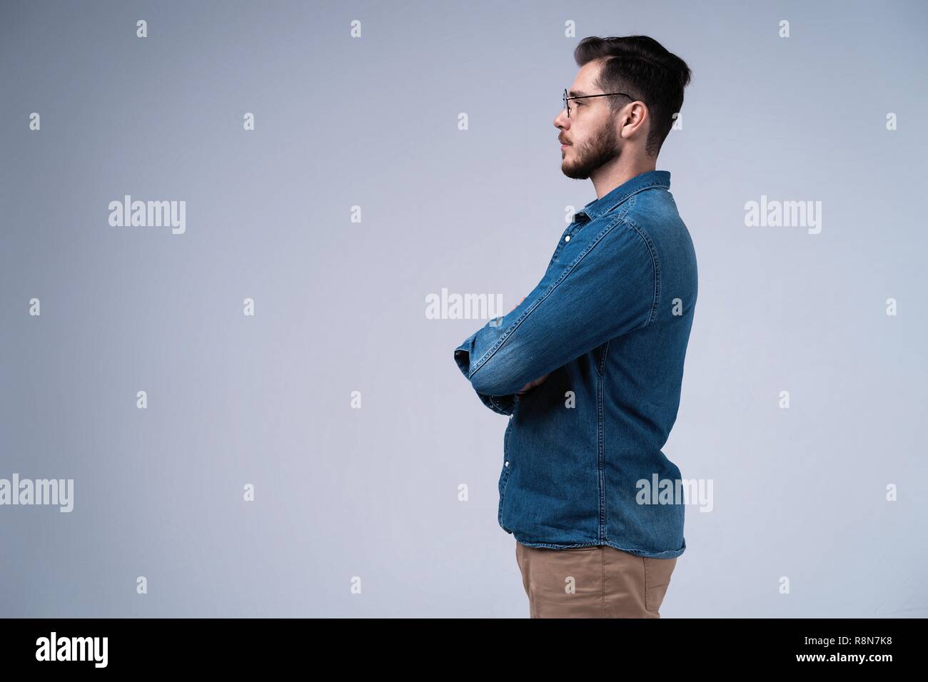 Portrait of fashionable bel homme en jeans shirt traversant les mains et regarde la caméra. Banque D'Images