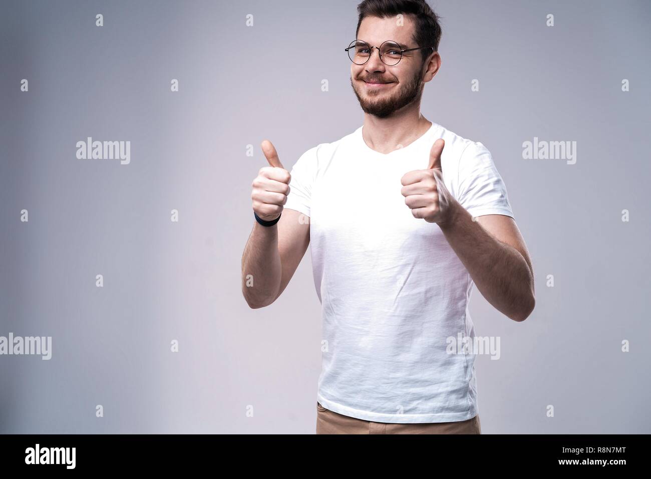 Portrait of a smiling man showing thumb up sur fond gris. Banque D'Images