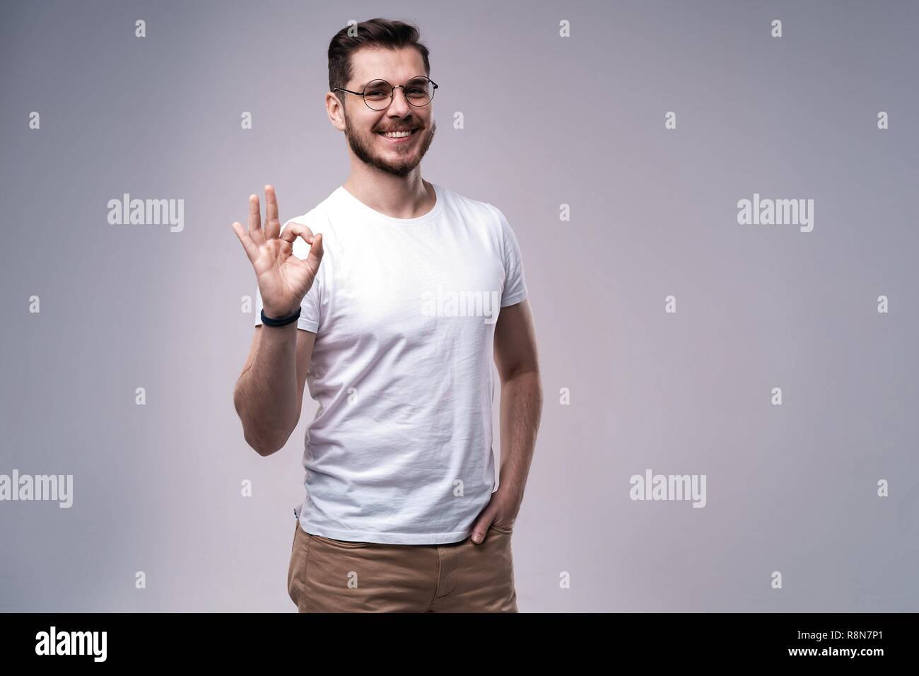 Portrait of a smiling man showing thumb up sur fond gris. Banque D'Images