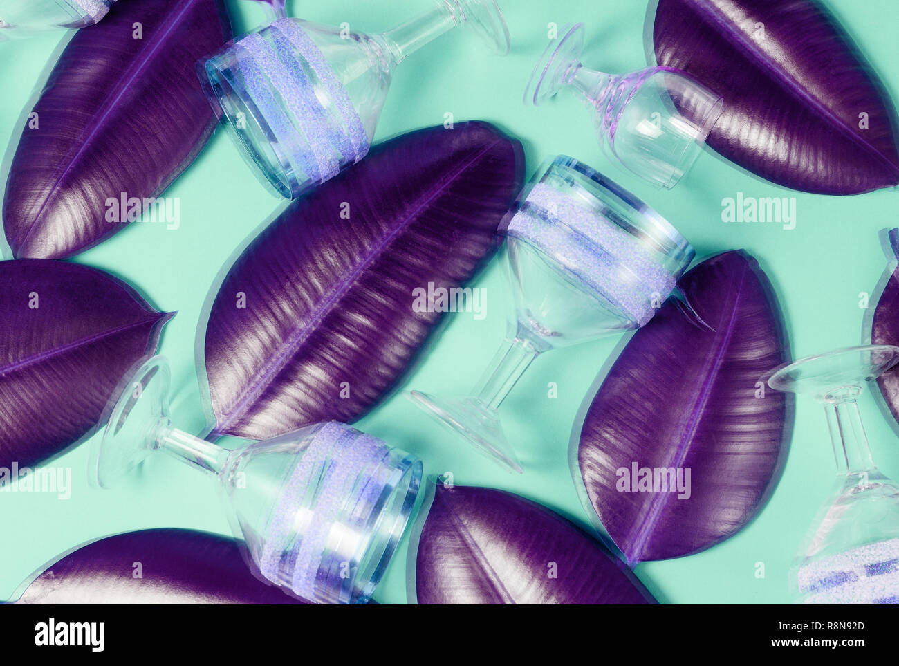 Résumé Contexte holographique effet sur mise en page avec des verres à vin vintage vide et vert feuilles tropicales de ficus. Banque D'Images