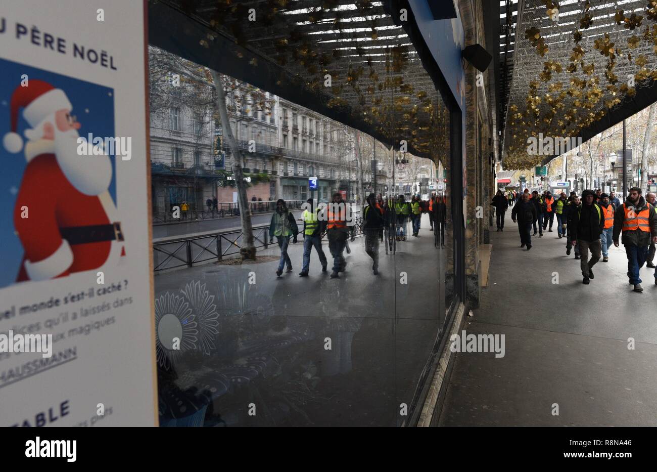 Décembre 08, 2018 - Paris, France : Gilet jaune protestataires se reflètent  dans les vitres de la boutique de luxe des Galeries Lafayette comme ils se  dirigent vers l'avenue des Champs-Élysées. Manifestation