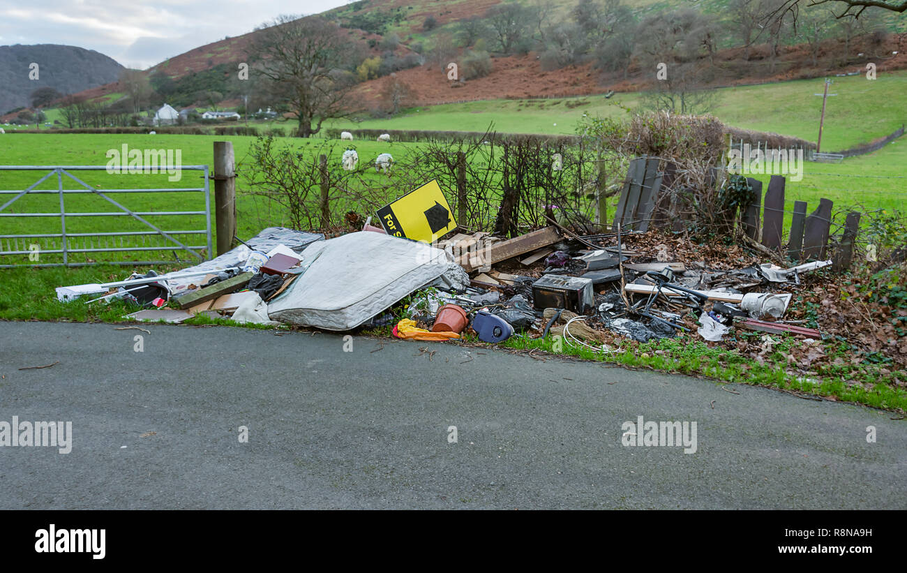 Dans un quartier calme et paisible, une mouche tipper a disposé des ordures et des déchets par la haie et la porte d'un champ d'agriculteurs Banque D'Images