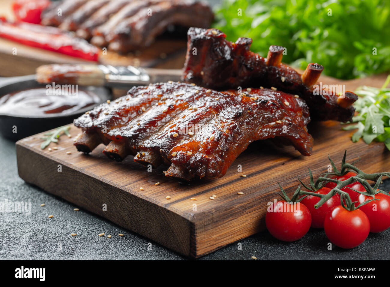 Gros plan du porc grillé à la sauce barbecue et caramélisées dans du miel. Délicieux en-cas à la bière sur une planche en bois pour la production de béton sur fond sombre Banque D'Images