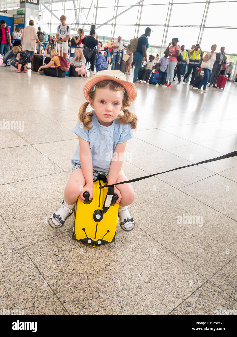 Fatigué enfant de quatre ans à l'aéroport, assis sur sa petite valise Trunki Banque D'Images