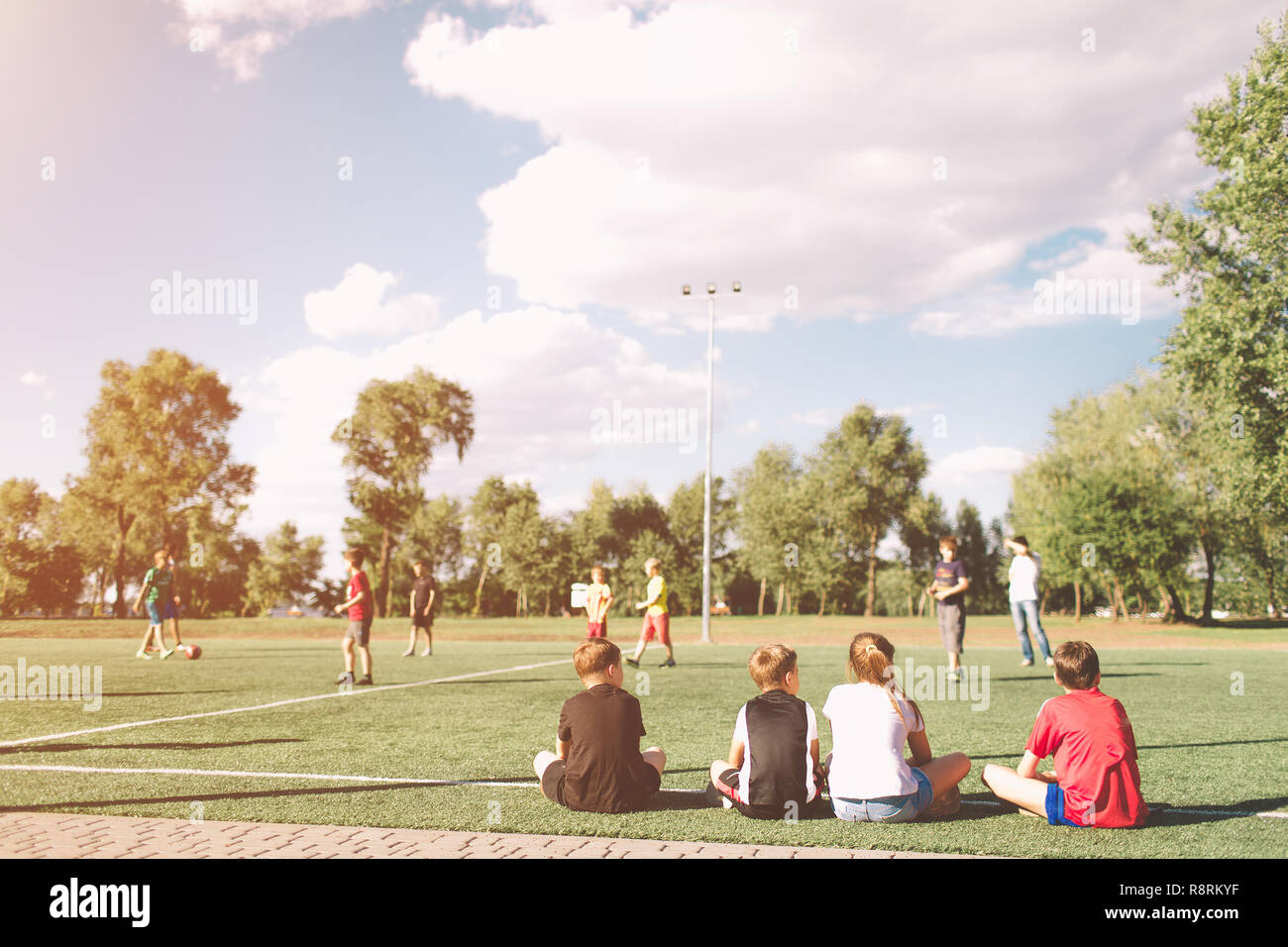 L'équipe de soccer des enfants jouer match. Jeu de football pour les enfants. Les jeunes joueurs de soccer assis sur ton. Les petits enfants en bleu et rouge Maillot Sportswear en attente dans une out. Banque D'Images