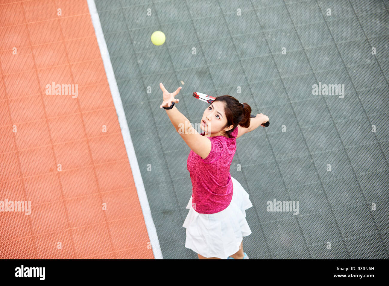 Young Asian tennis player servant dans match Banque D'Images