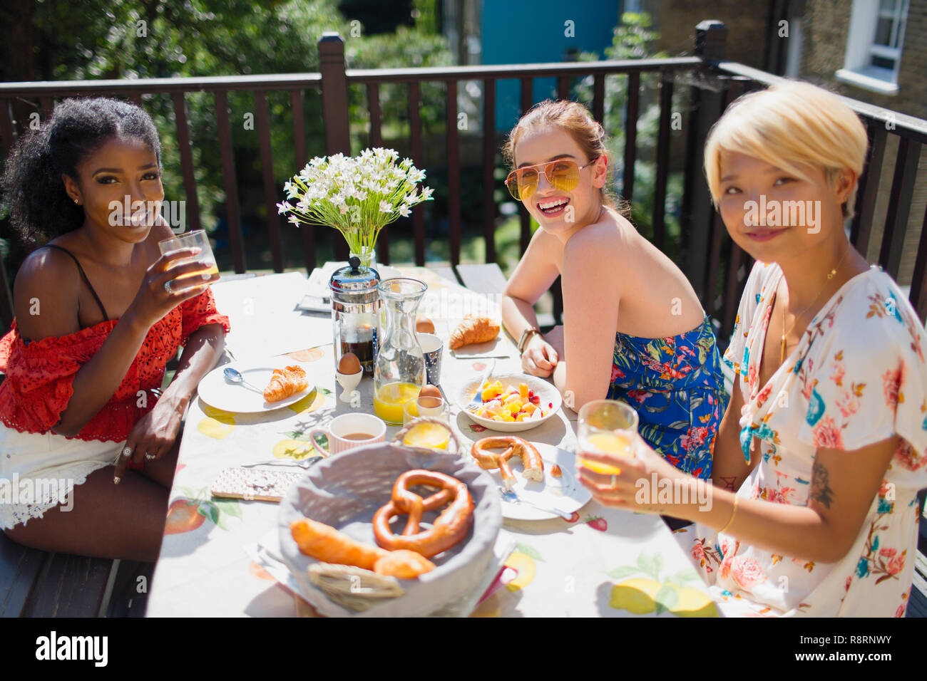 Portrait smiling young women enjoying brunch sur balcon ensoleillé Banque D'Images