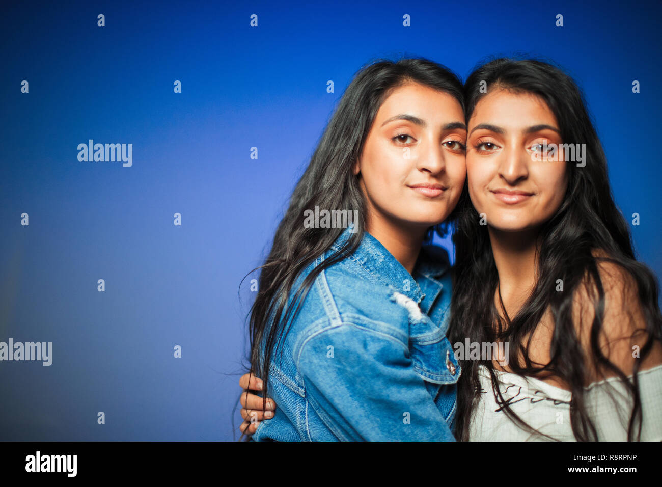 Portrait confiant teenage twin sisters hugging Banque D'Images