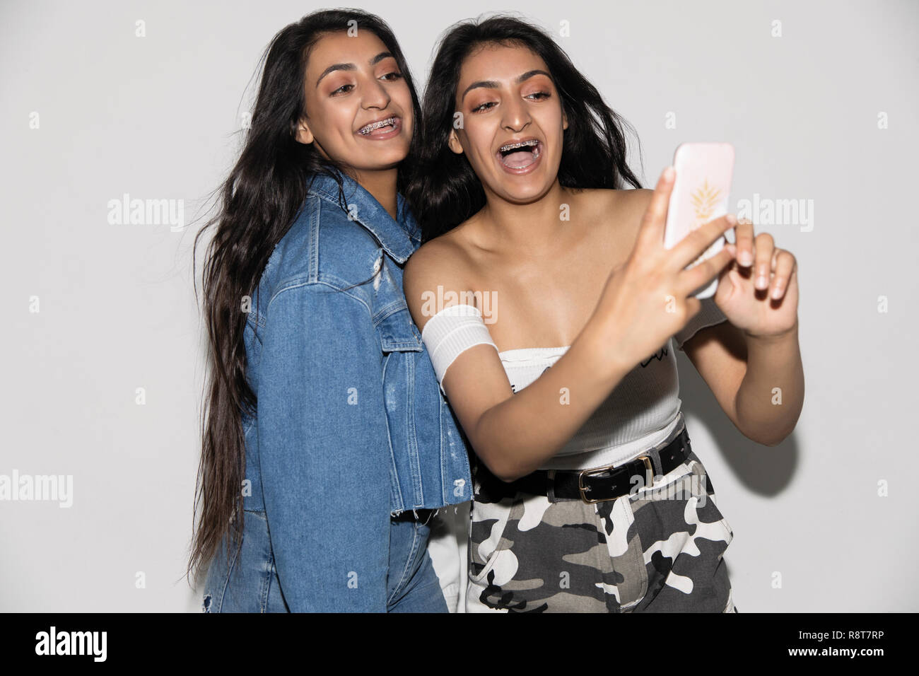 Teenage Twin Sisters en tenant avec selfies smart phone Banque D'Images