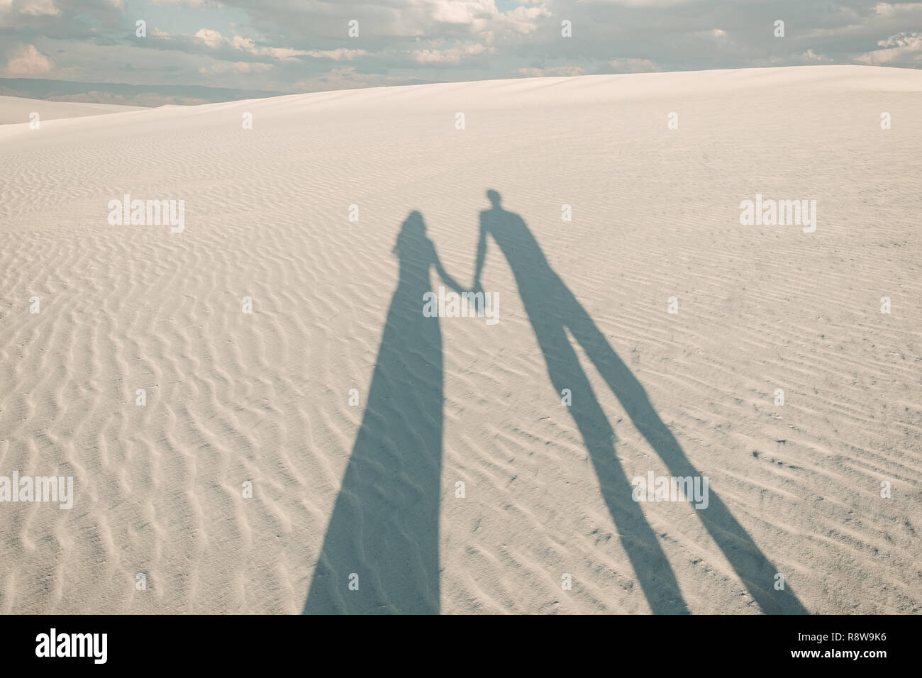 La silhouette d'un garçon et une fille se tenant la main sur le sable de sable blanc National Monument à New Mexico, USA Banque D'Images