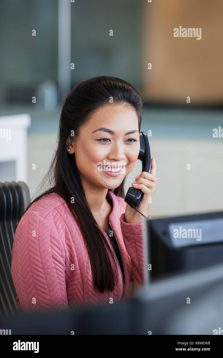 Smiling businesswoman talking on telephone in office Banque D'Images