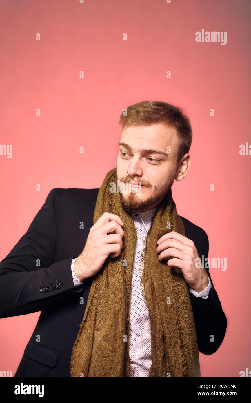 Un jeune homme, 29 ans, posant avec un costume et une écharpe, à côté. pink background, studio shot, séance photo. Banque D'Images