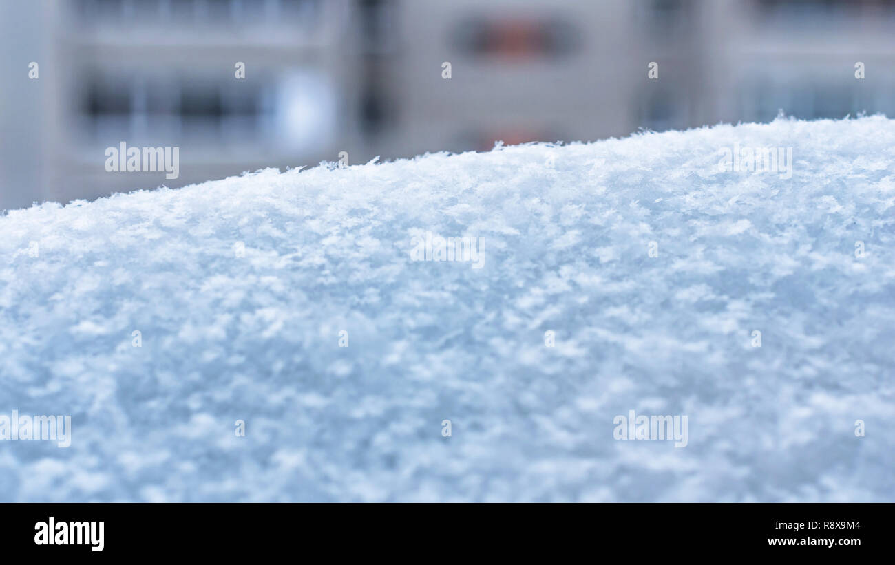 Un banc de neige avec les flocons de neige sur un immeuble d'arrière-plan. La saison d'hiver, la météo, le changement climatique de l'image. Banque D'Images