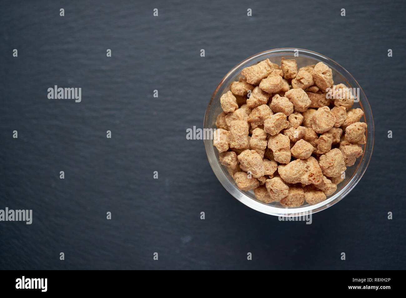 D'aliments sains et nutritifs de la viande de soja, de morceaux dans un bol blanc. Vue de dessus du soja brut morceaux dans le bol sur fond sombre. Banque D'Images