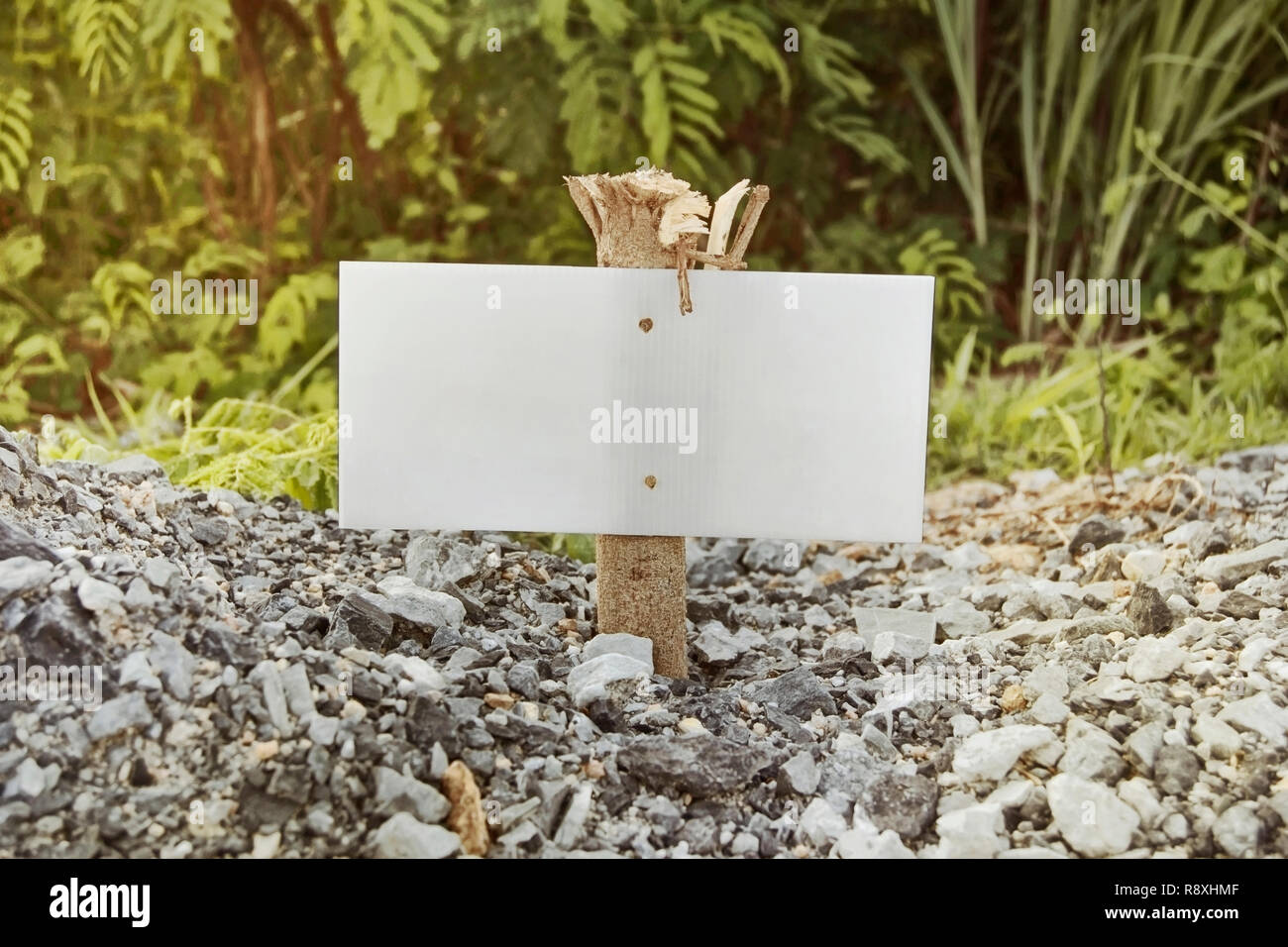 La plaque blanche sur une petite colonne en bois sur fond de pierres et des  verts dans la journée ensoleillée Photo Stock - Alamy