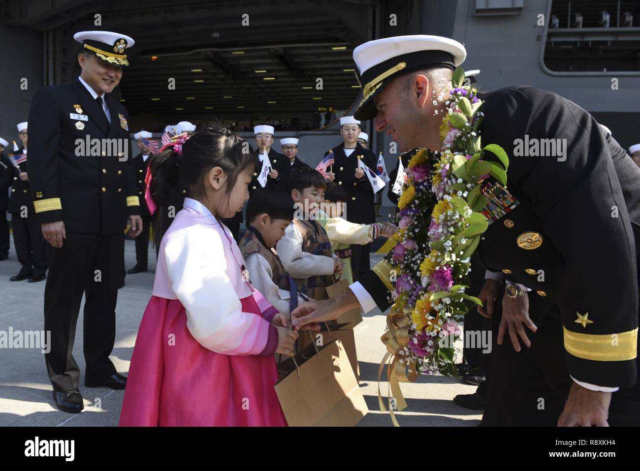 BUSAN, République de Corée (15 mars 2017) Arrière Adm. James W. Kilby, commandant du Groupe aéronaval 1 donne un don à la République de Corée (ROK) enfant pendant un échange de cadeaux dans le cadre de l'USS Carl Vinson (CVN-70) Arrivée à l'administration centrale de la flotte de la République de Corée dans le cadre d'une visite du port de routine. Le groupe aéronaval du Carl Vinson est en fonction d'un programme de déploiement de l'ouest du Pacifique dans le cadre de la flotte américaine du Pacifique visant à étendre la commande et des fonctions de contrôle U.S. 3e flotte. Banque D'Images