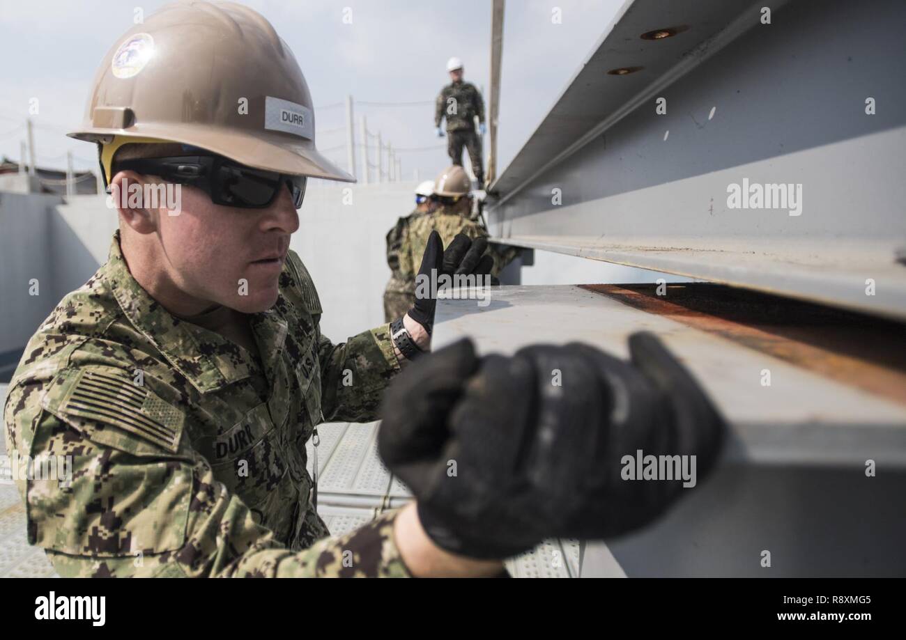 Constructionman Builder Apprentice Travis Durr, affectés à la construction navale, 5 Bataillon Mobile guides une poutre en I à la République de Corée (ROK) l'éducation et de la formation navale en commande Jinhae, Corée, le 14 mars 2017, dans le cadre de l'exercice Foal Eagle 2017. Foal Eagle est un exercice d'entraînement bilatéral annuel, conçu pour améliorer l'état de préparation des forces des États-Unis et de la République de Corée et de leur capacité à travailler ensemble durant une crise. Banque D'Images