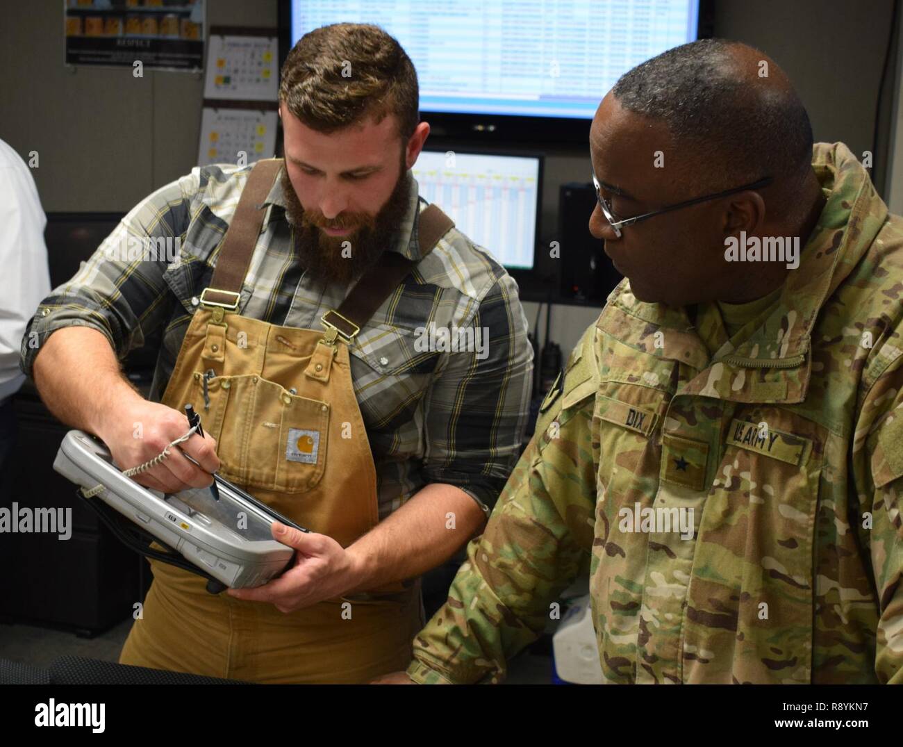 Dustin Cox (à gauche), un manutentionnaire, explique comment l'Armée Grue Depot Operations a exploré l'utilisation de comprimés dans ses opérations logistiques de munitions à Brigue. Le général Richard B. Dix, général commandant, Commandement Munitions conjointe, lors de sa visite à munitions de l'Armée grue, l'activité de l'Indiana. Les comprimés pourrait potentiellement réduire le temps de déplacement des équipes sur le terrain, réduire les formalités administratives et de créer une plus grande visibilité de l'information à travers l'ensemble de la direction. Banque D'Images