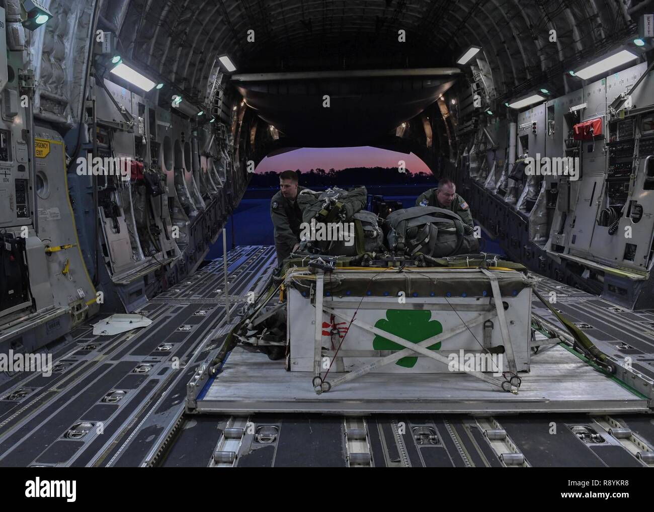 Airman Senior Grant Smart, gauche, 15e Escadron de transport aérien (COMME) l'arrimeur, et capitaine principal Sgt. Tony Viventi, droite, 15e comme arrimeur, pousser une palette de chargement sur un C-17 Globemaster III sur la base commune Charleston flightline, 15 mars 2017. Le vol, pour la première fois en plus de 10 ans où des équipages d'AERPS portaient l'équipement. AERPS équipement consiste en un masque de caoutchouc, de multiples couches de bottes et de gants, filtre de ventilateur et système audio et un système d'enceintes. Banque D'Images