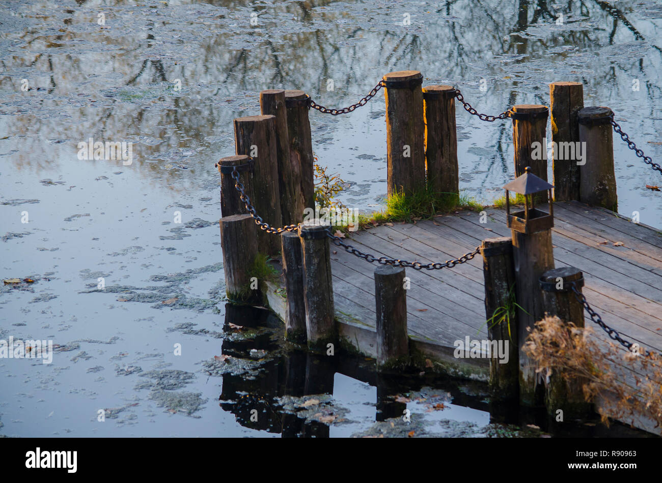 Le vieux pont est un pont sur une rivière de journaux reliés par des chaînes. Dans la rivière, le reflet des arbres. Banque D'Images