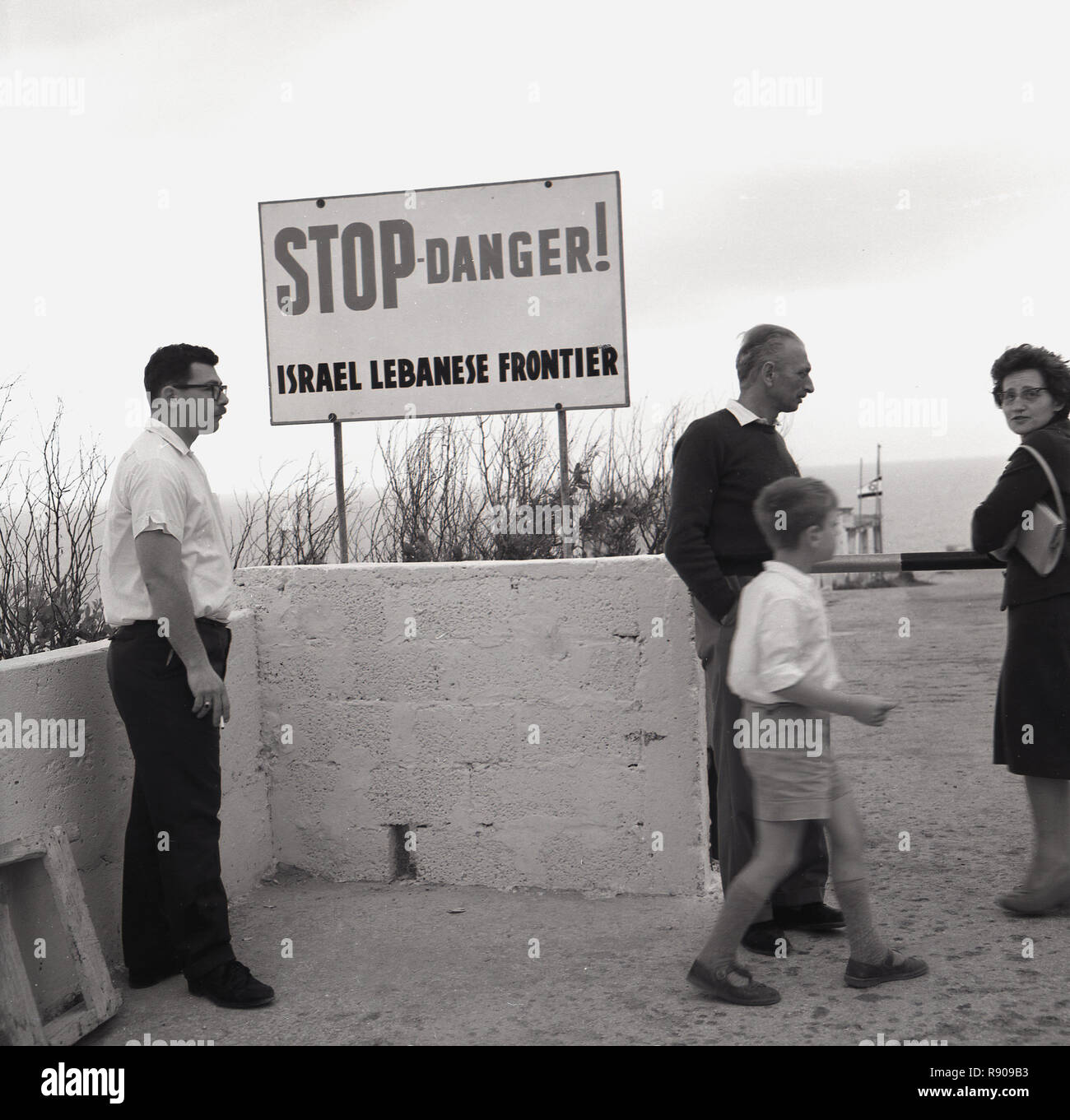 Années 1950, Israël, les gens à la frontière entre Israël et le Liban Comité permanent par un Stop-Danger signe. La tension entre les deux pays depuis la brève guerre avec la Ligue arabe en 1948, plus exactement le territoire et les droits dus pour les peuples de la Palestine se poursuivra pendant le reste du siècle et au-delà. Banque D'Images