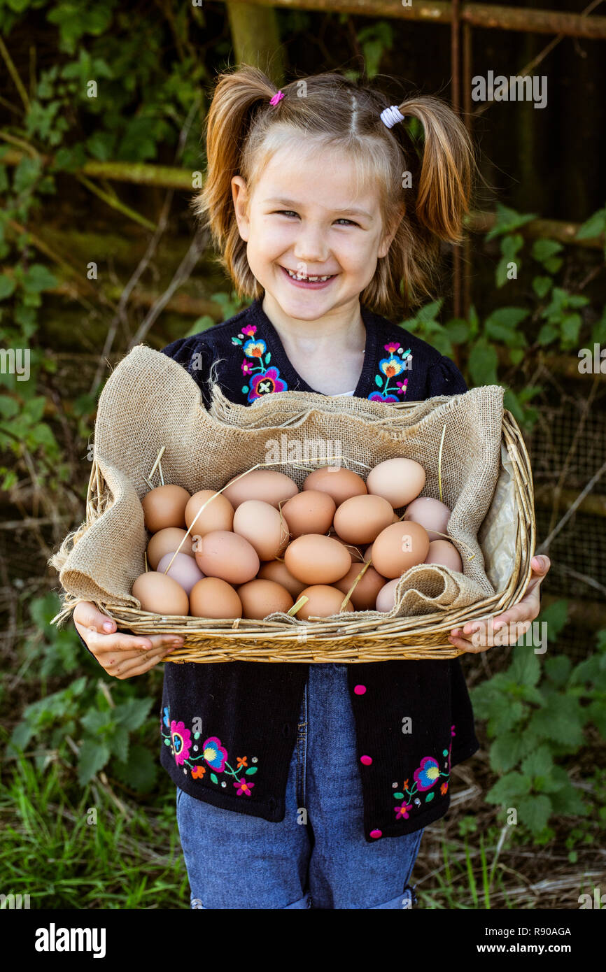 Smiling girl holding basket avec des oeufs, looking at camera. Banque D'Images