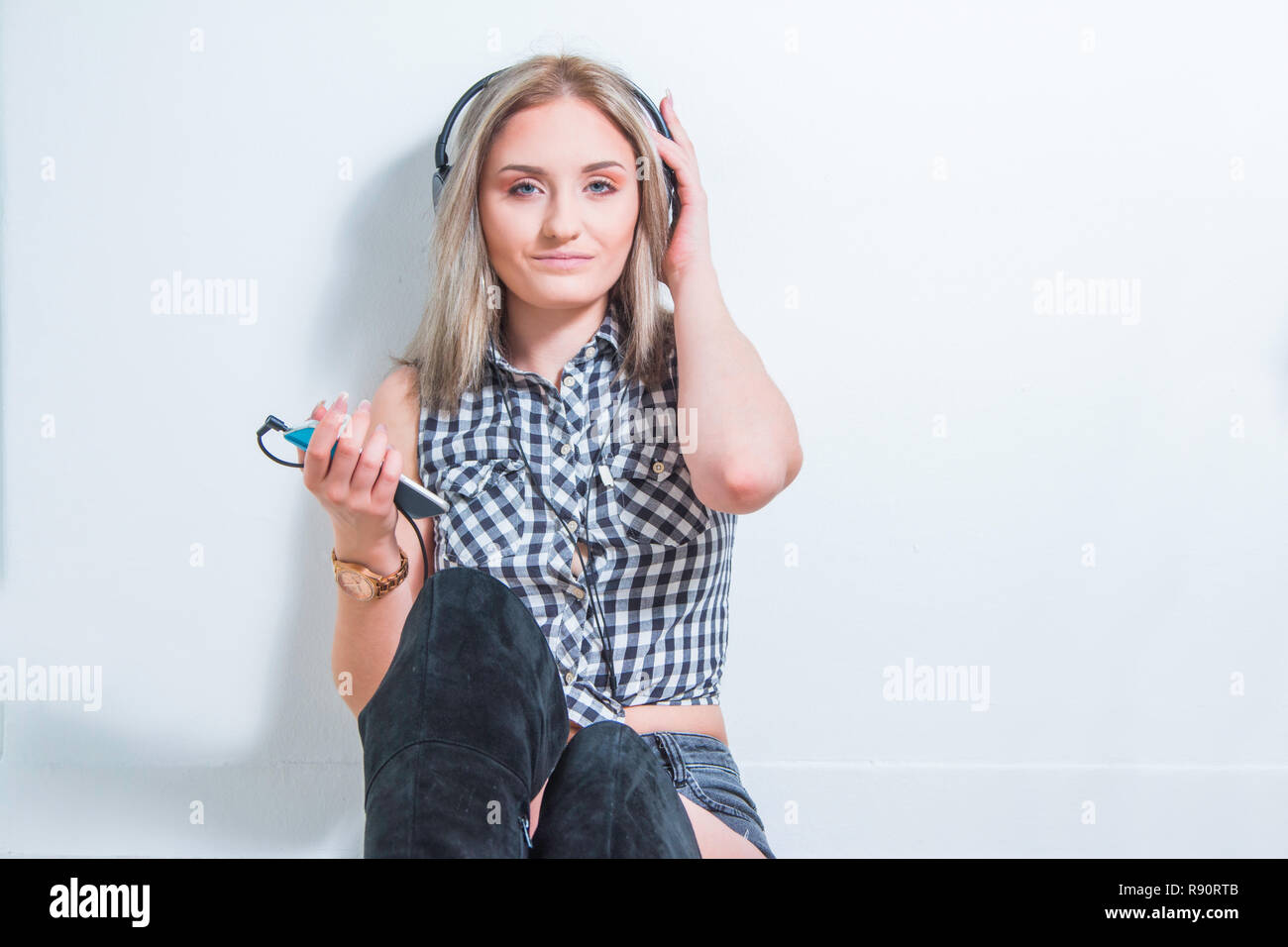 Belle jeune fille en chemise à carreaux avec des écouteurs et smart phone profiter de la musique à la maison. Concept de musique pour la jeunesse. Banque D'Images
