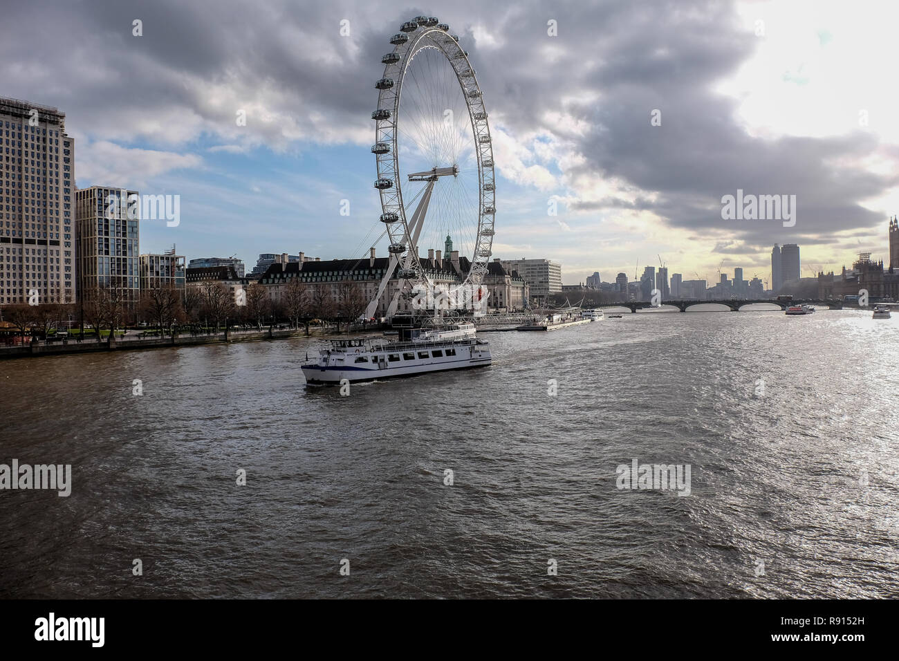 Londres, Royaume-Uni, 30 Jan 2018 : un bateau-ferry passe devant l'Oeil de Londres sur la Tamise sur un jour nuageux. Banque D'Images