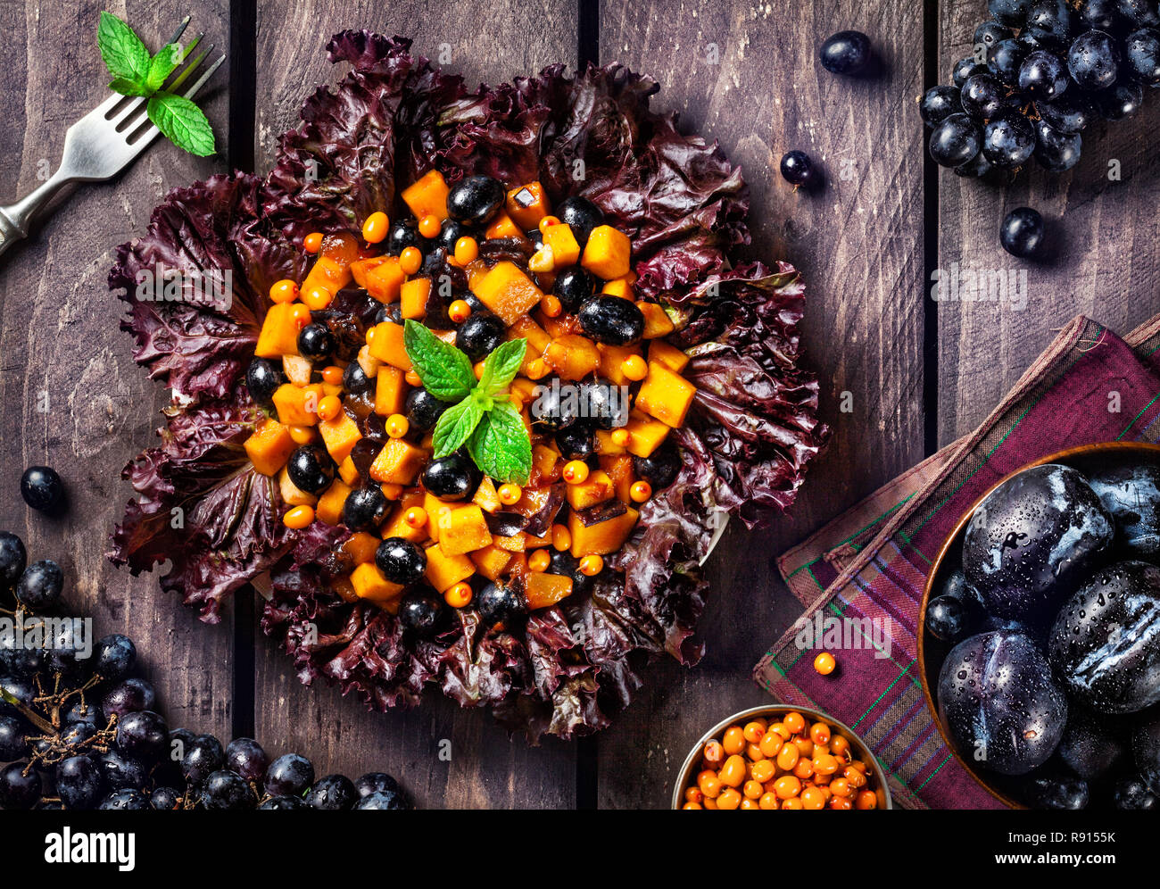 De potiron salade de fruits, les prunes, les raisins et la menthe sur fond de bois Banque D'Images