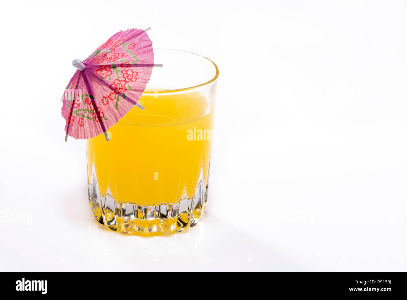 Boisson à l'orange avec parapluie cocktail, isolé sur blanc. Banque D'Images