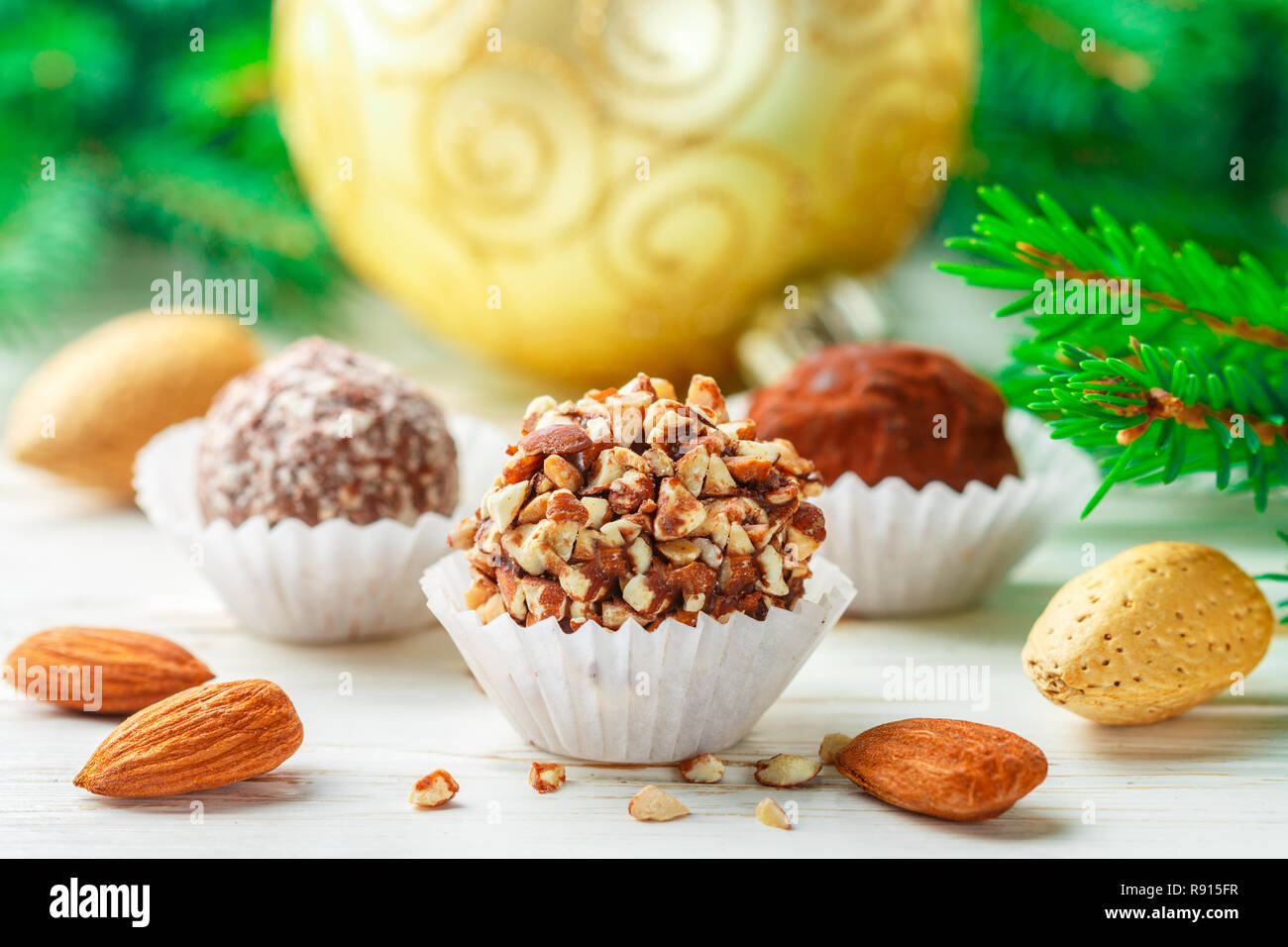 Truffes au chocolat maison avec amandes, noix de coco et de biscuits en miettes une plaque blanche sur la table avec des branches de sapin et boules de jouets de fête. Cadeau pour Banque D'Images