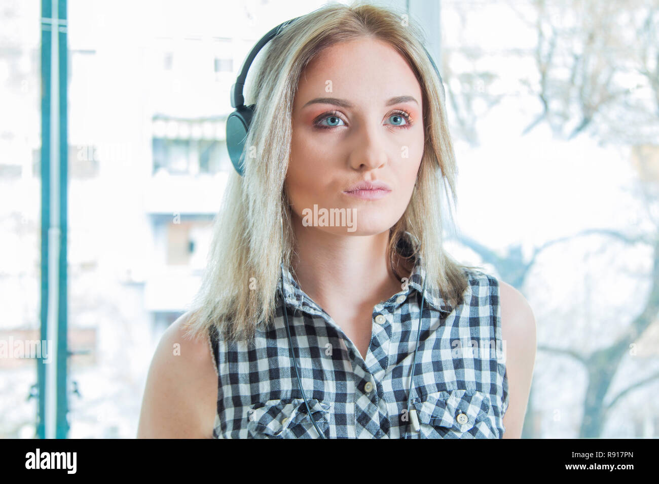 Belle jeune fille en chemise à carreaux avec des écouteurs et smart phone profiter de la musique à la maison. Concept de musique pour la jeunesse. Banque D'Images