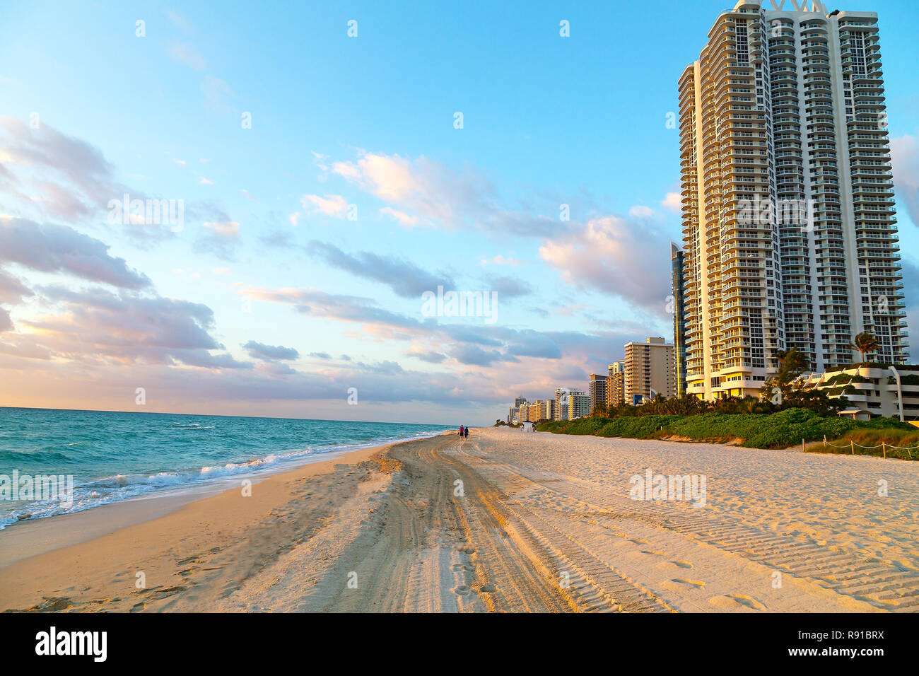 Lever du soleil à Miami Beach, en Floride. Le soleil du matin met en lumière les couleurs douces d'une plage de sable et de bâtiments. Banque D'Images