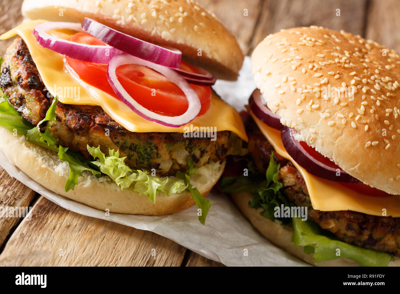 Avec Veggie burger de la laitue fraîche, les oignons, les tomates et le fromage cheddar close-up sur la table horizontale. Banque D'Images