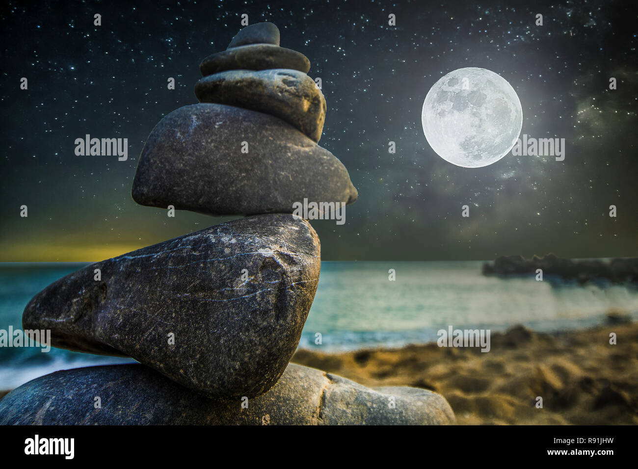 Cairn de pierre sur la plage de sable, sur l'arrière-plan un ciel étoilé de nuit avec lune, concept de zen Banque D'Images