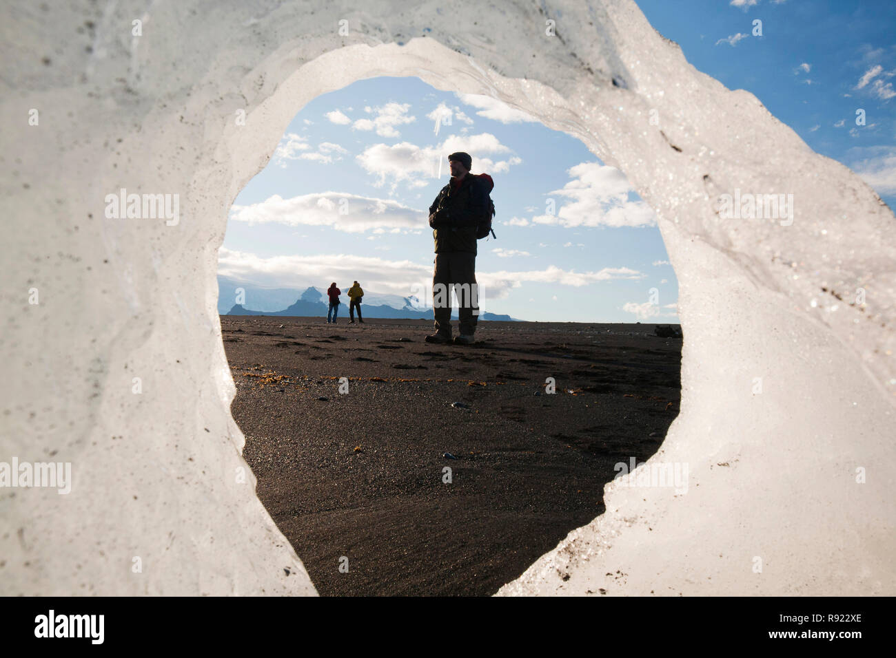 Un touriste au lagon glaciaire Jökulsárlón encadrée par un melting ice berg. Jokulsarlon est l'un des endroits les plus visités de l'Islande. Il a été créé par la régression rapide du glacier Breidamerkurjokull qui balaie en bas de la calotte glaciaire de Vatnajokull. Ice bergs mettent bas à l'avant et flotter dans le lagon avant de flotter sur la mer quand assez petit. Tous les glaciers reculent rapidement, et sont prévus pour disparaitre complètement dans les 100 prochaines années. Les films Batman et James Bond ont été filmés à la lagune de glace. Banque D'Images