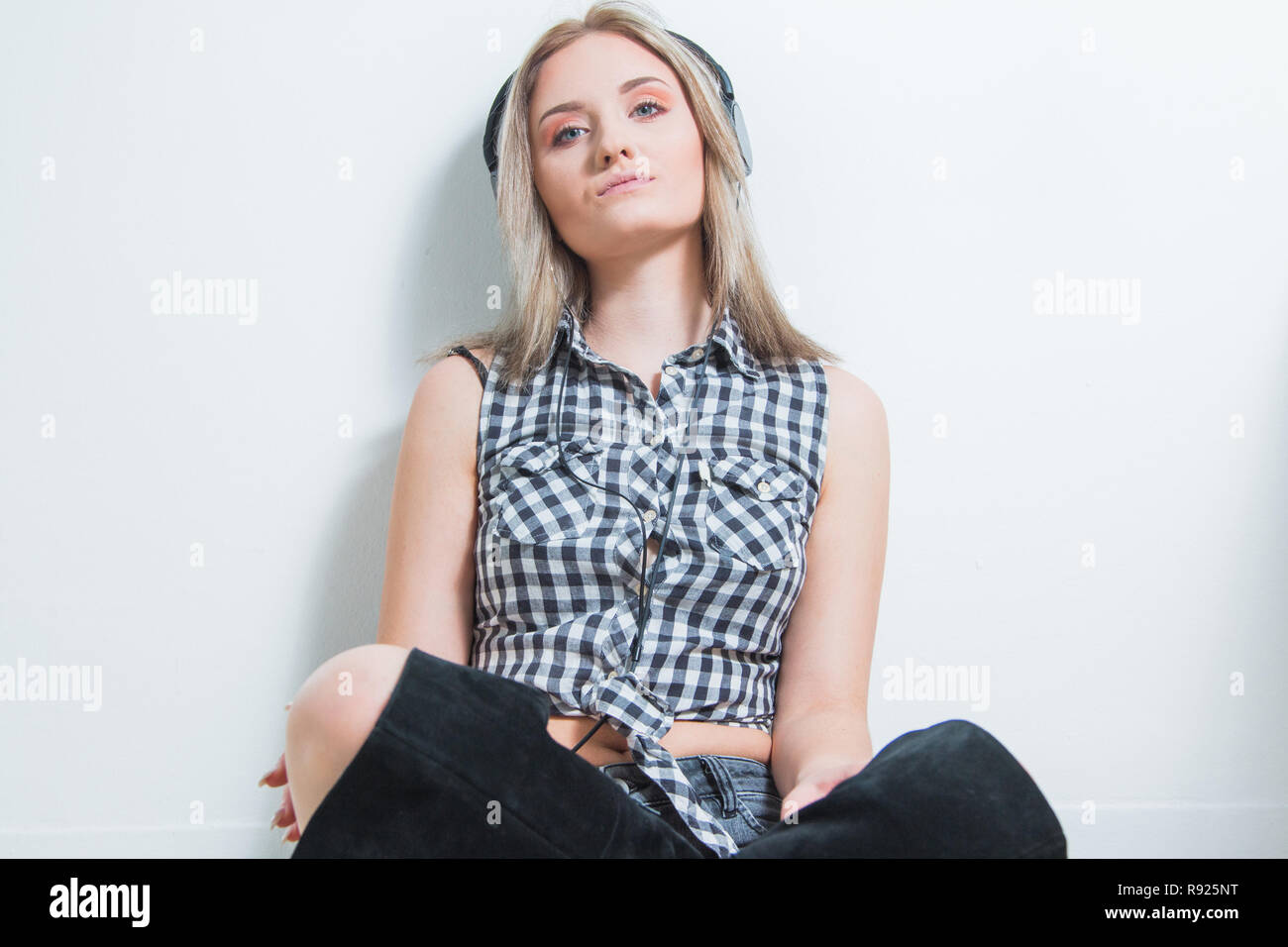 Belle jeune fille en chemise à carreaux avec des écouteurs et smart phone profiter de la musique à la maison. Concept de musique pour la jeunesse. Banque D'Images