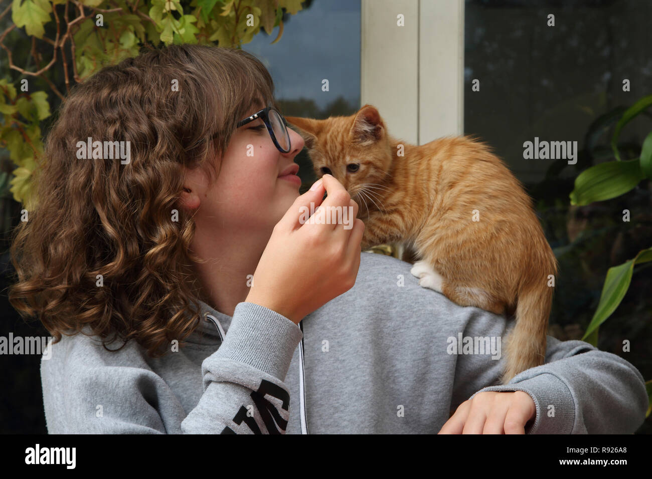 12 ans, fille au gingembre et chaton blanc de grimper sur son épaule Surrey England Banque D'Images