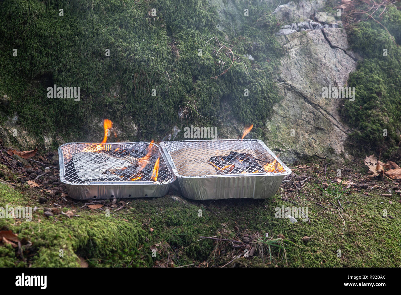 Un couple des barbecues jetables étant incendiés dans perparation pour certains la cuisson. Banque D'Images